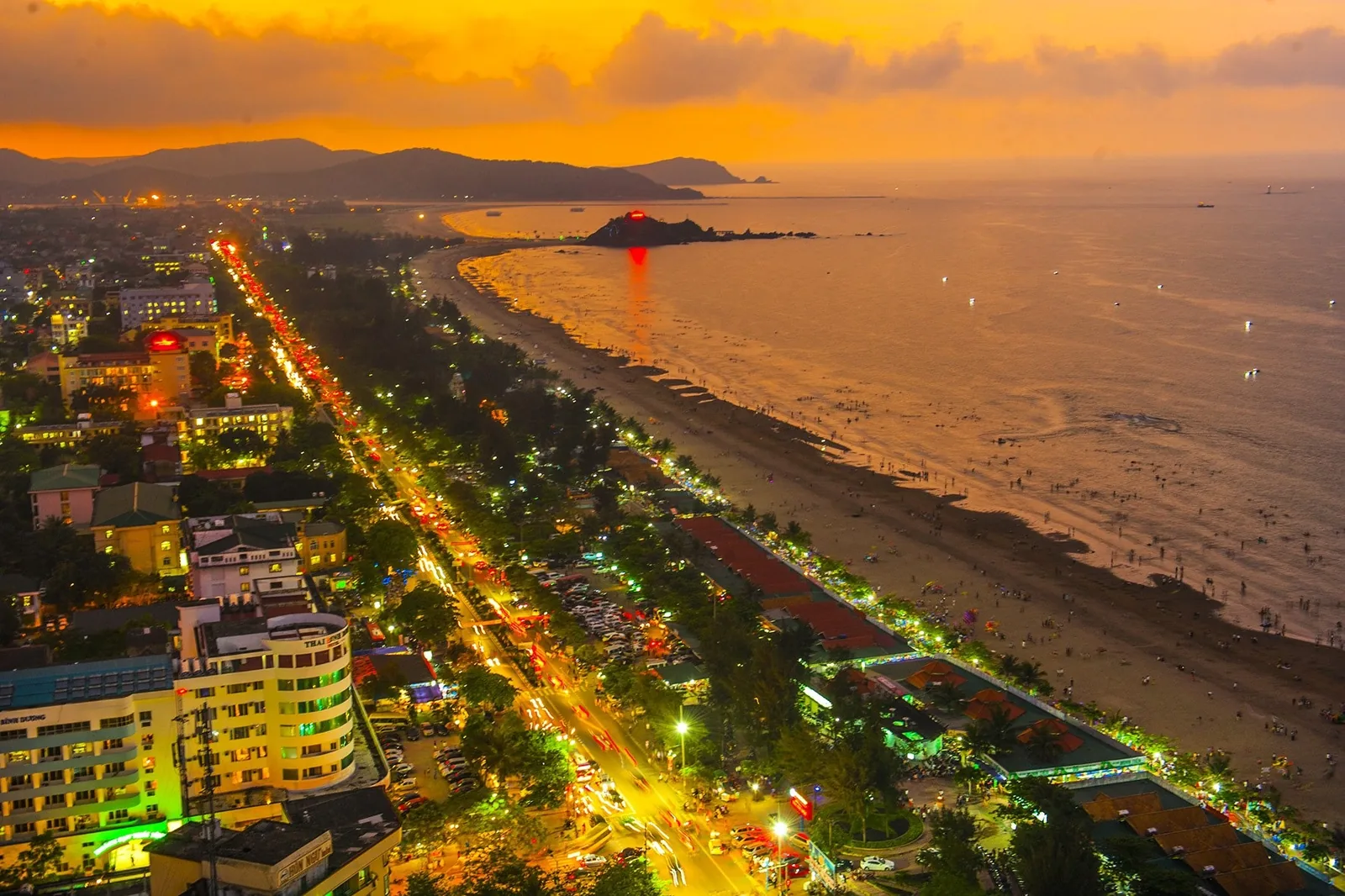 Toàn cảnh trên cao lúc hoàng hôn của bãi biển Cửa Lò với đường ven biển, nhà cửa sáng đèn và bờ cong ở Nghệ An. Toàn cảnh trên cao lúc hoàng hôn của bãi biển Cửa Lò với đường ven biển, nhà cửa sáng đèn và bờ cong ở Nghệ An.
